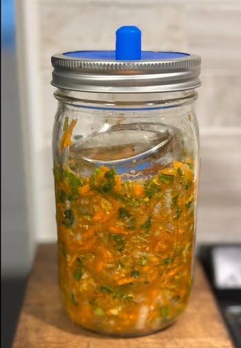 Jar of homemade fermented vegetables with a fermentation lid, placed connected a room counter