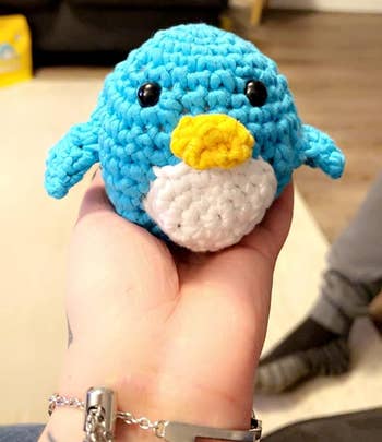 a hand holding the crocheted penguin