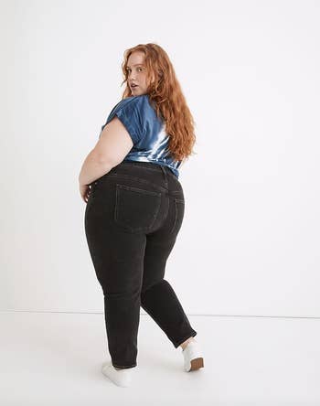 Model in a pair of black straight leg jeans showing pockets in the back 