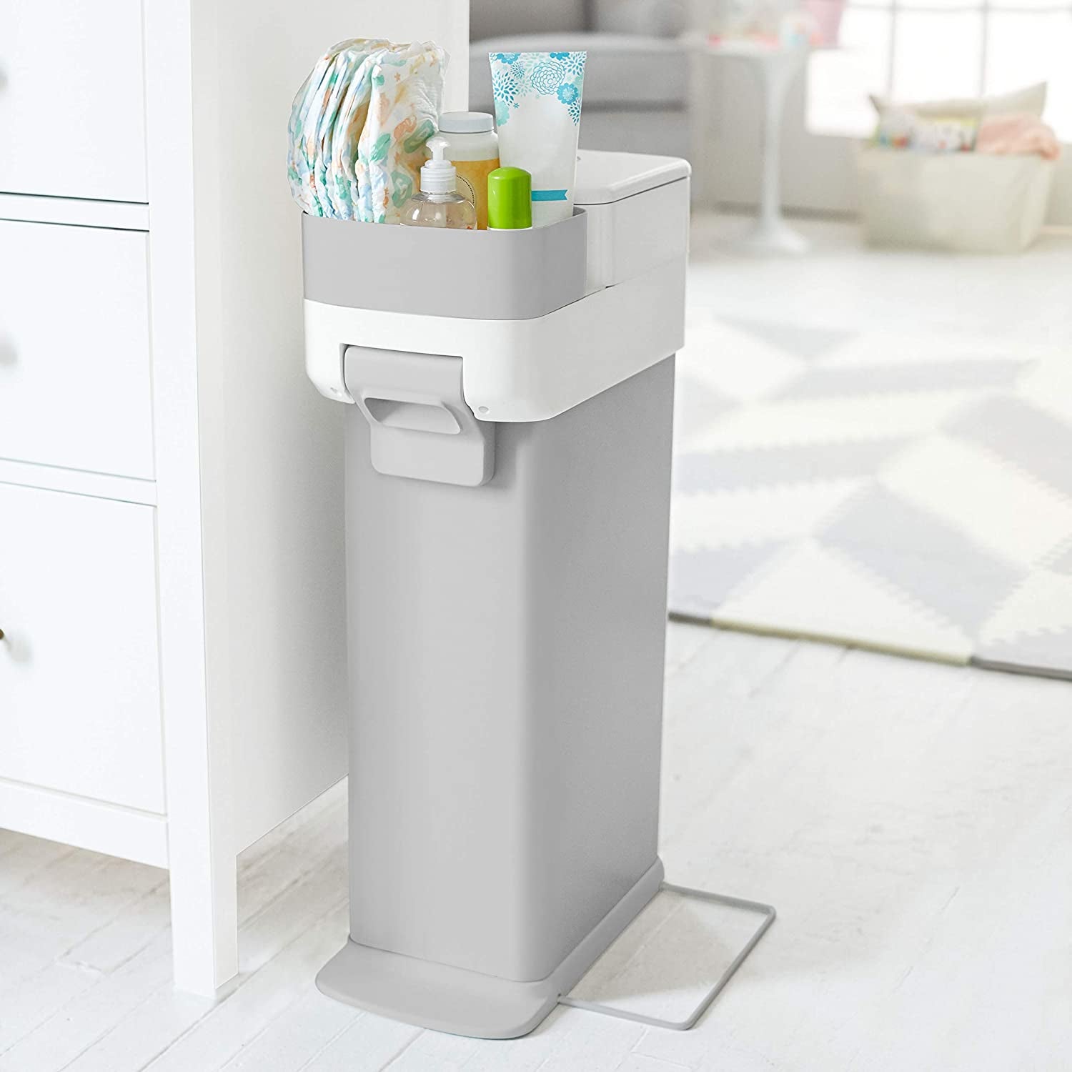 a gray diaper trash can with a caddy on top