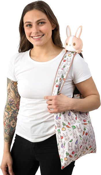 model carrying bunny and vegetable print tote with plush bunny on shoulder