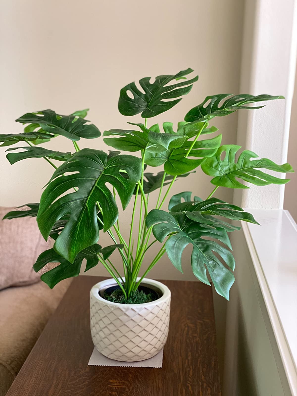 Reviewer image of fake palm tree in a white ridged pot on top of a dark wooden cabinet