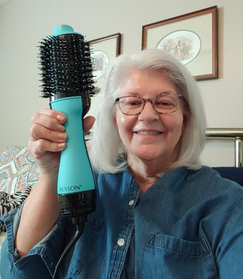 on right, reviewer with silver blow-dried shoulder-length hair holds blue Revlon One-Step Drying Brush