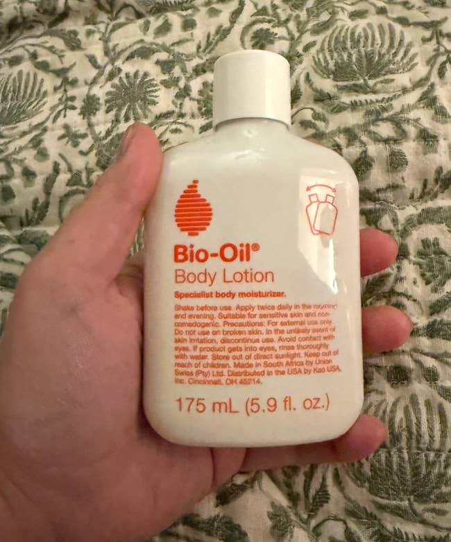 Hand holding a 175 mL vessel of Bio-Oil Body Lotion, featuring merchandise details successful orangish text