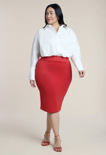 Person successful  a achromatic  blouse and reddish  skirt lasting  confidently, wearing reddish  heels. Fashionable attire suitable for buying  nonfiction  context
