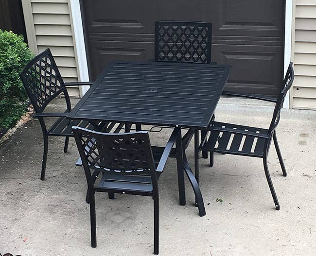 Reviewer image of four black wrought iron chairs around a square iron table on pavement