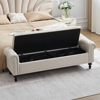 Storage seat  with tufted back, unfastened  to uncover  compartments. Placed astatine  ft  of a furniture  with pillows, successful  a furnished chamber  setting