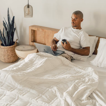 A model sitting in bed under the comforter