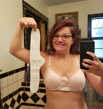 reviewer holding up a bra liner while showing one under their bra