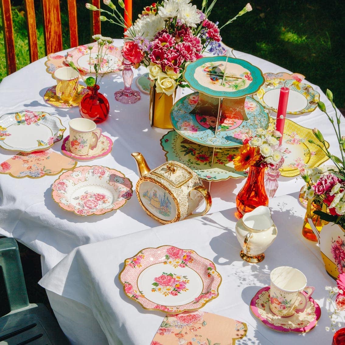 a tea time display on a table with several floral paper plates and other cutlery and decor