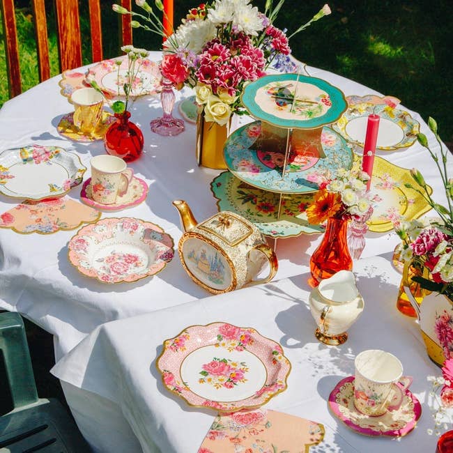 a tea time display on a table with several floral paper plates and other cutlery and decor
