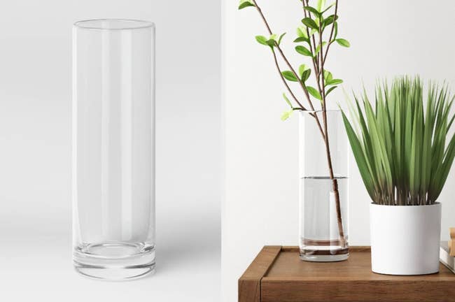 Tall narrow clear vase on a gray background, product with stem inside of it on table next to white vase with plant