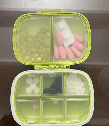 reviewer photo of the green pill organizer, which is open and filled with pills in its large and small compartments