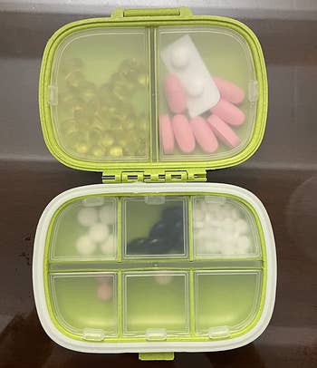 reviewer photo of the green pill organizer, which is open and filled with pills in its large and small compartments