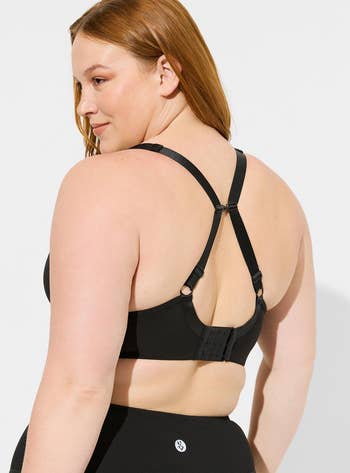 Model in black sports bra with adjustable straps and a clasp back