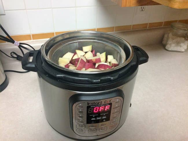 A reviewer's Instant Pot with a strainer full of potatoes inside