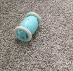 Aqua blue alarm clock rolling on a carpeted floor