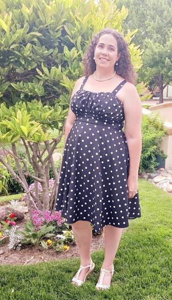 Person in a polka dot dress smiling in a garden, showcasing a chic summer outfit suitable for outdoor events