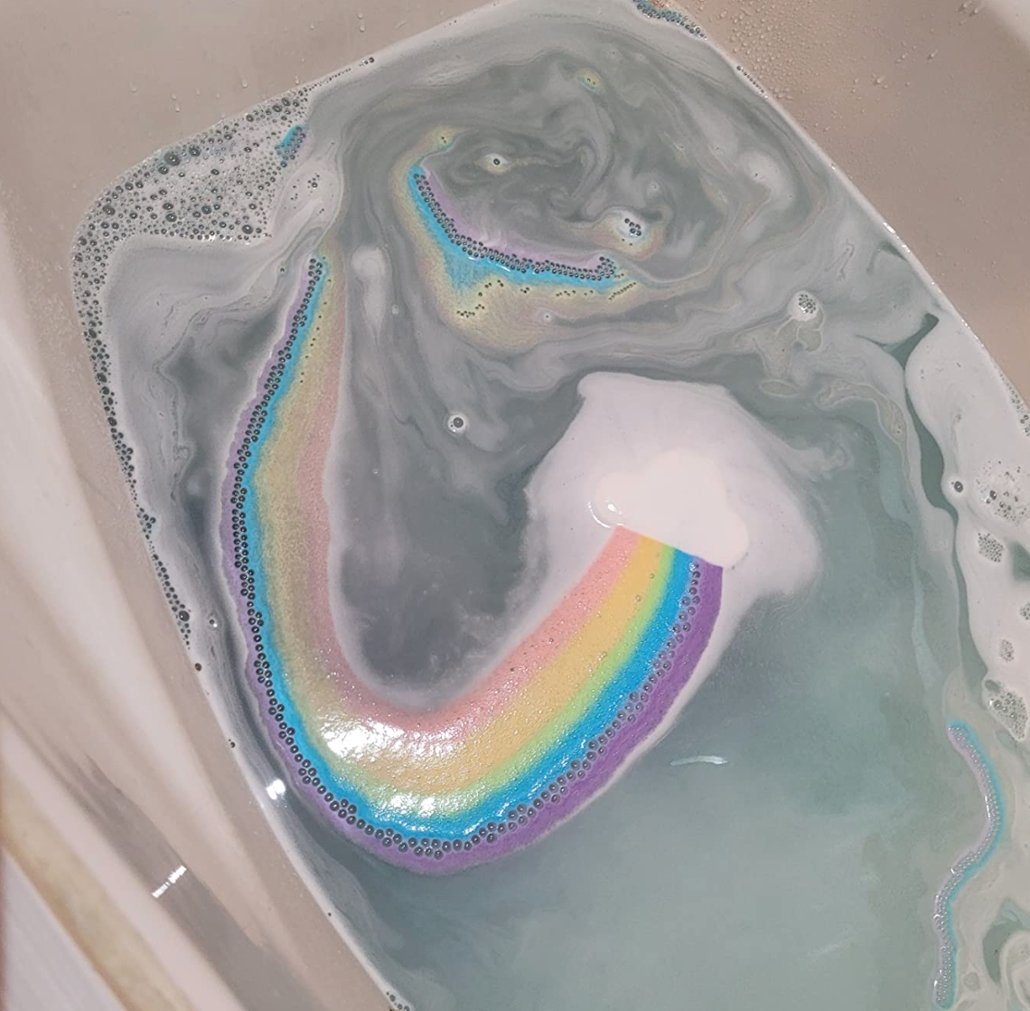 A rainbow bath fizz streaking color across the water 