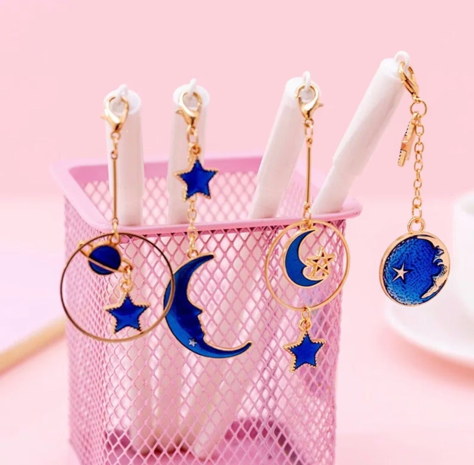 white pens with gold and blue charms dangling off cap