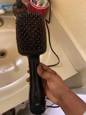 Reviewer holding black and pink hot brush