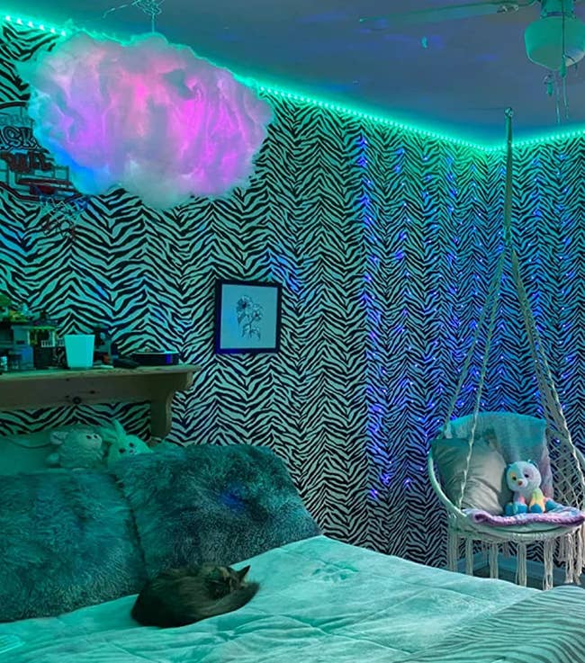 A reviewer's room with the blue and purple lit up cloud floating above their bed