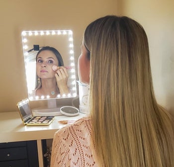 reviewer doing her makeup in lighted mirror