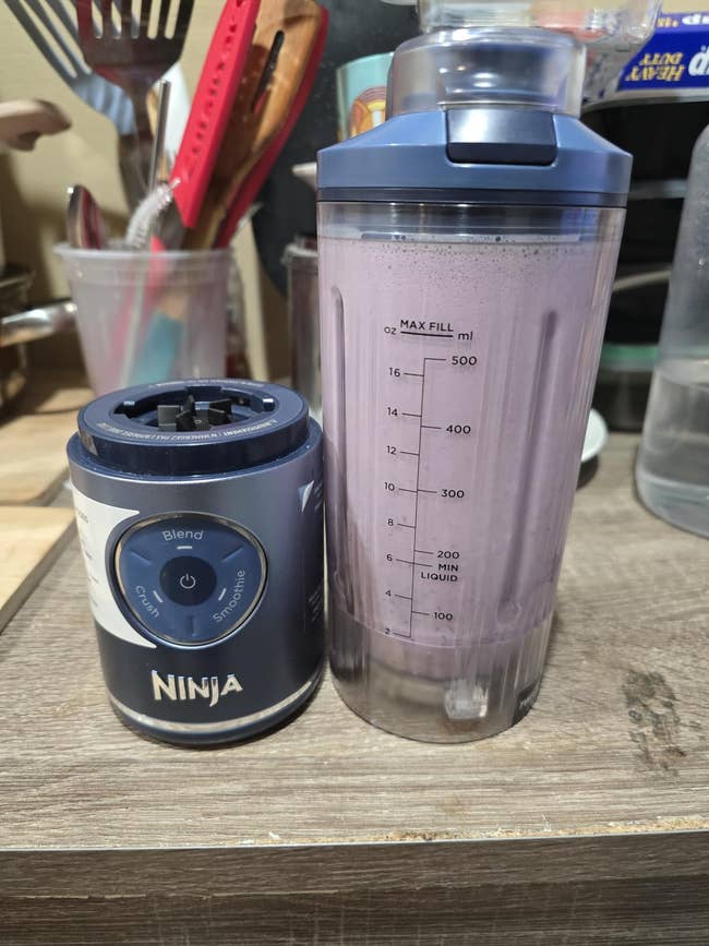 Ninja blender with a smoothie successful  a wide   cupful  connected  a room  counter, surrounded by utensils and bottles