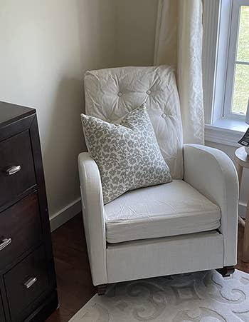 Reviewer image of upholstered tufted white rocking chair with a floral white and gray throw pillow