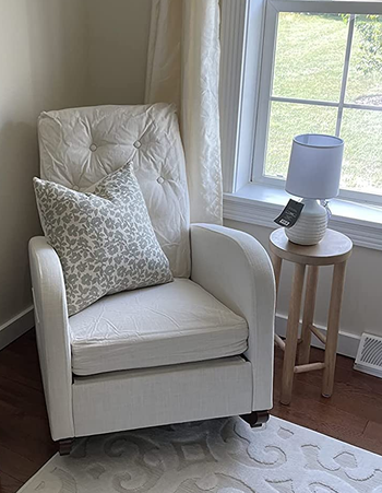 Reviewer image of upholstered tufted white rocking chair with a floral white and gray throw pillow