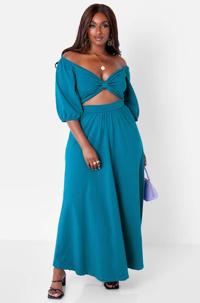model in teal dress with waist cutout and elbow sleeves