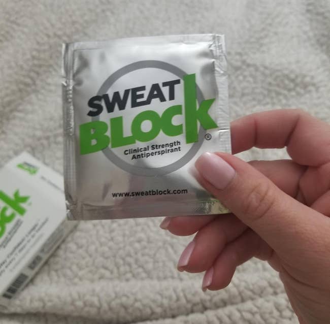 reviewer holding a packet of the Sweat Block wipes