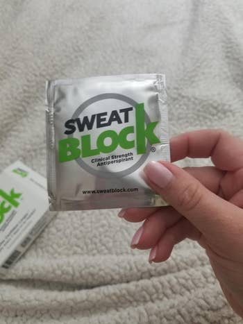 another reviewer holding a packet of the Sweat Block wipes