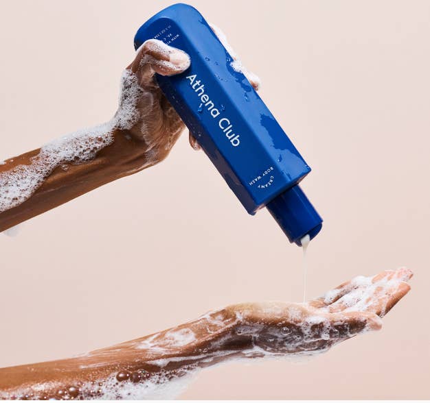 model holding bottle of body wash with arms covered in suds