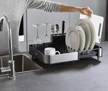 the extended dish rack filled filled with clean plates, glasses, and cutlery