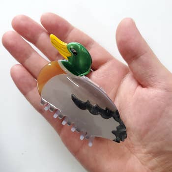 duck-shaped hair claw clip in the palm of a model's hand