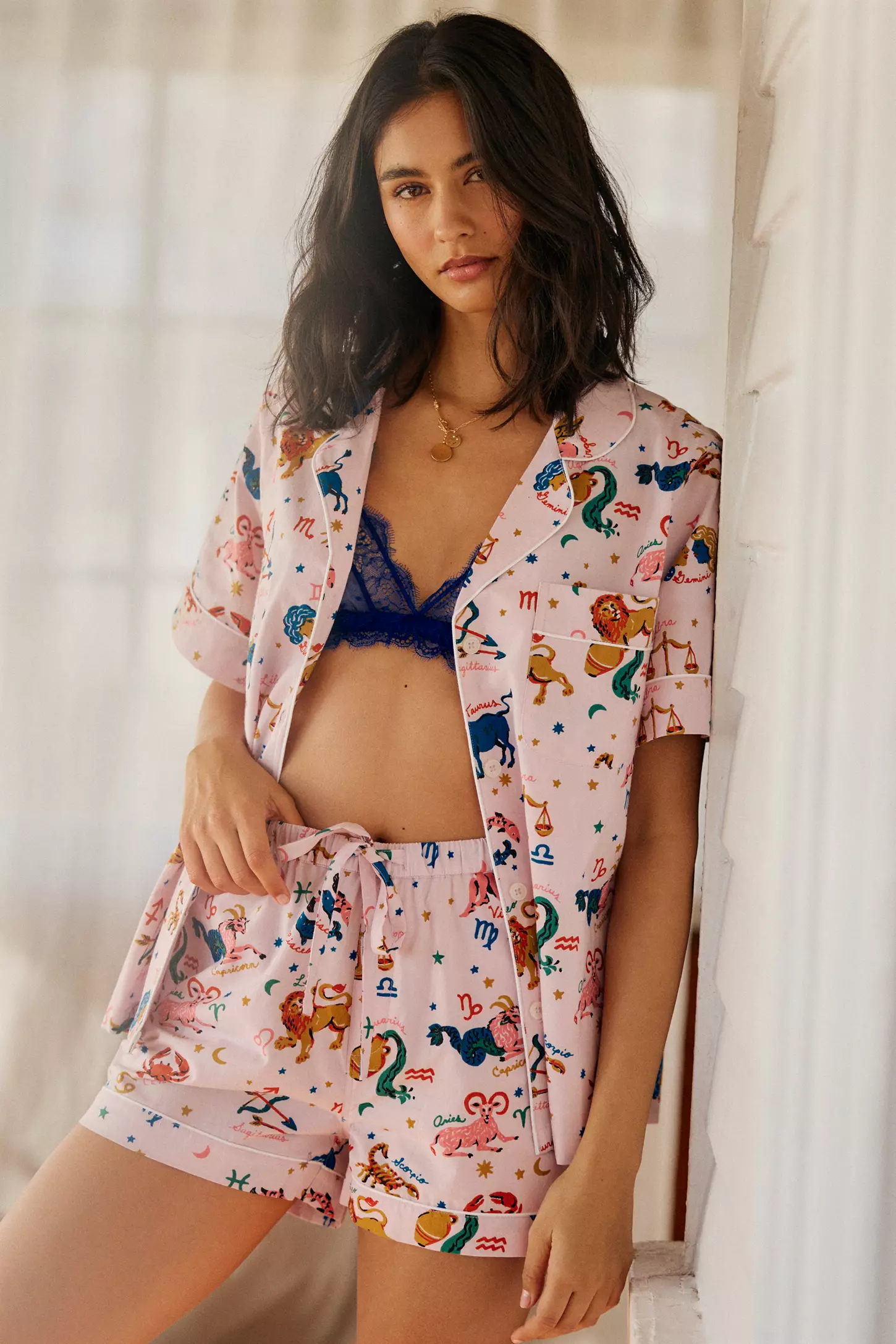 model in button up short pajama set with zodiac imagery