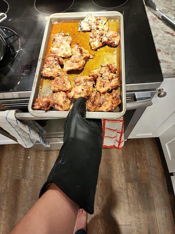 a reviewer wearing the black mitt pulling a tray out of the oven