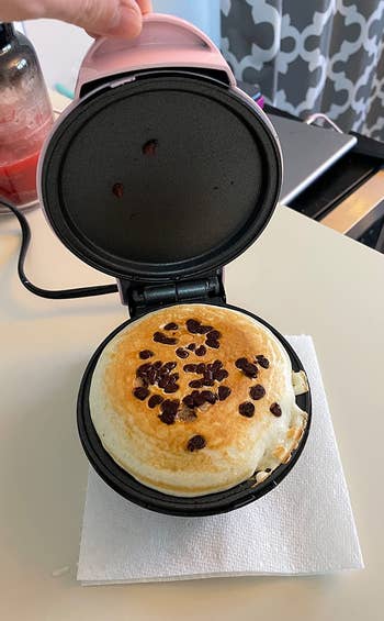 a chocolate chip pancake being cooked inside the mini maker