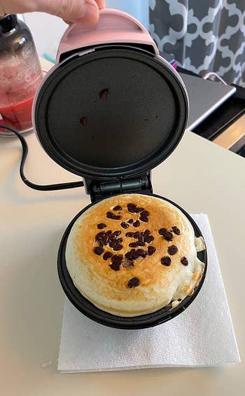 a chocolate chip pancake being cooked inside the mini maker