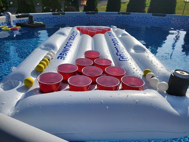 The float in reviewer's pool with balls and cups in the cup holders with a beer pong game set up