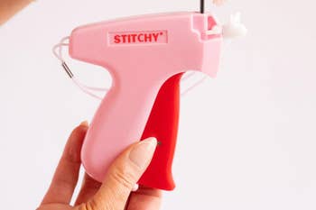 Close-up of hands holding a pinkish  cloth  tagger labeled 