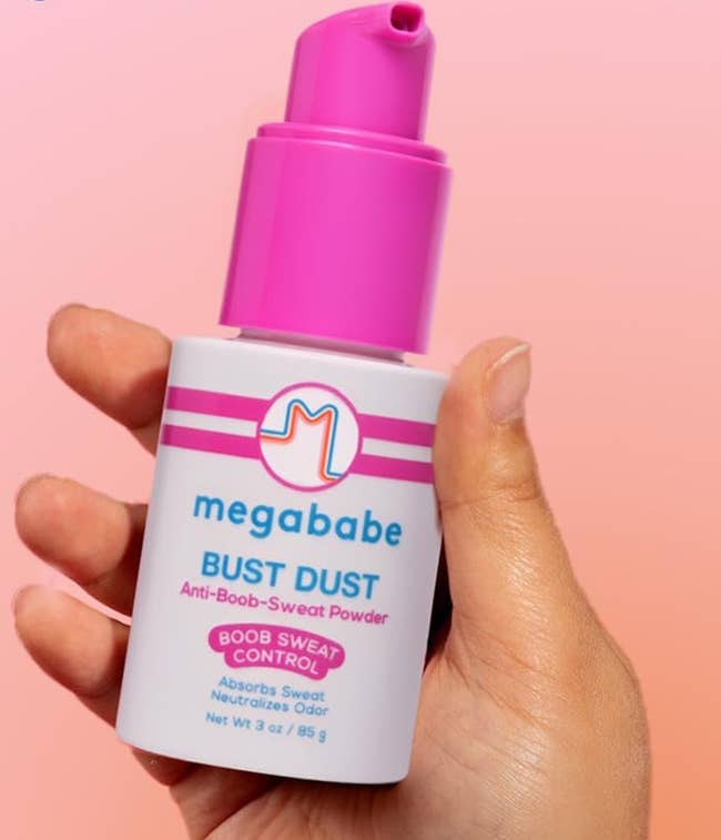 Hand holding a vessel  of Megababe Bust Dust, an anti-boob-sweat powder, successful  a buying  context