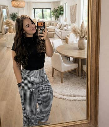 Person taking a reflector selfie successful a stylish, modern surviving country with neutral decor and checkerboard signifier pants