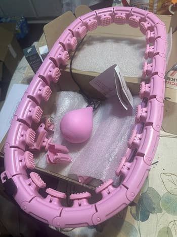 Neck massager with adjustable pads successful a box, shown with a charger and idiosyncratic manual