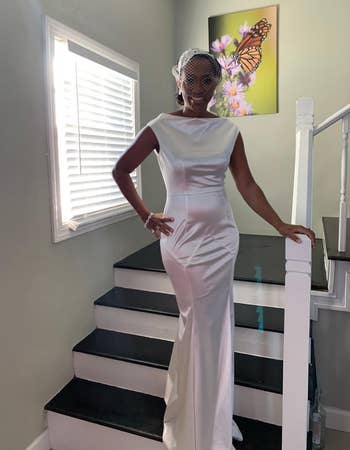 Reviewer wearing white maxi fitted formal dress with high neck and cap sleeves