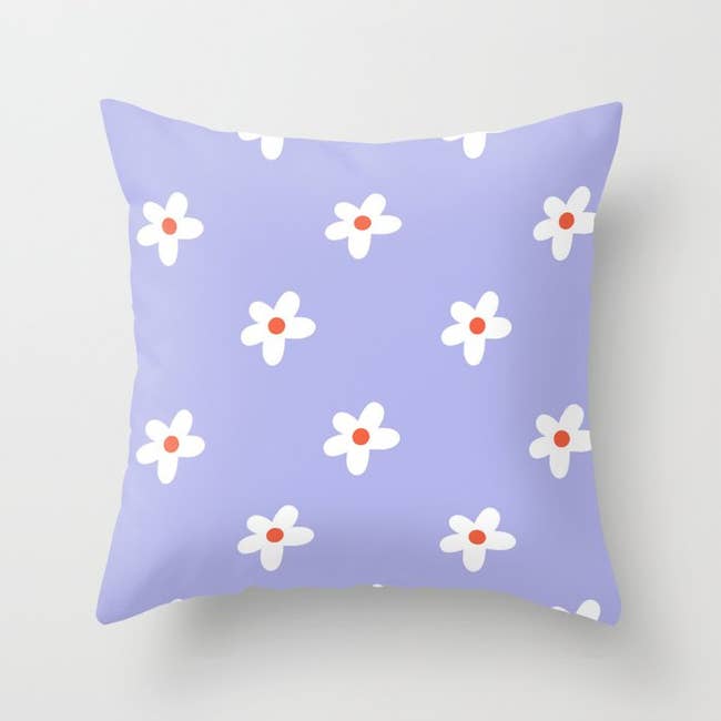 a purple throw pillow with a white floral pattern