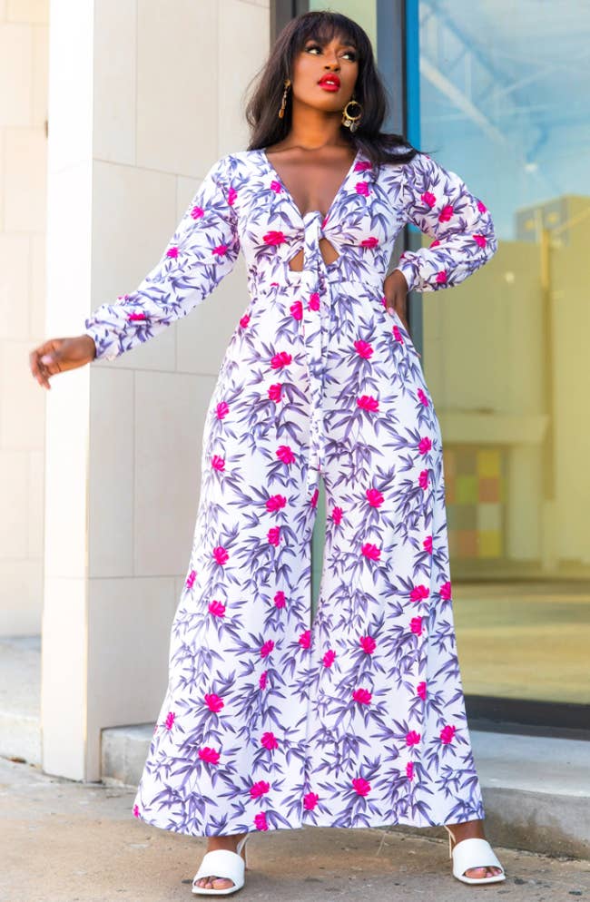model in long sleeve tie-front jumpsuit with floral pink and purple pattern