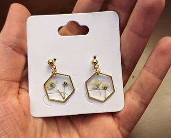 reviewer holding the pressed flower earrings