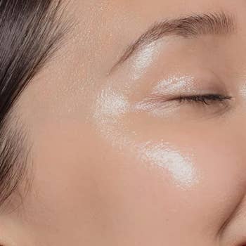 Close-up of a person's cheekbone with shiny highlighter makeup applied